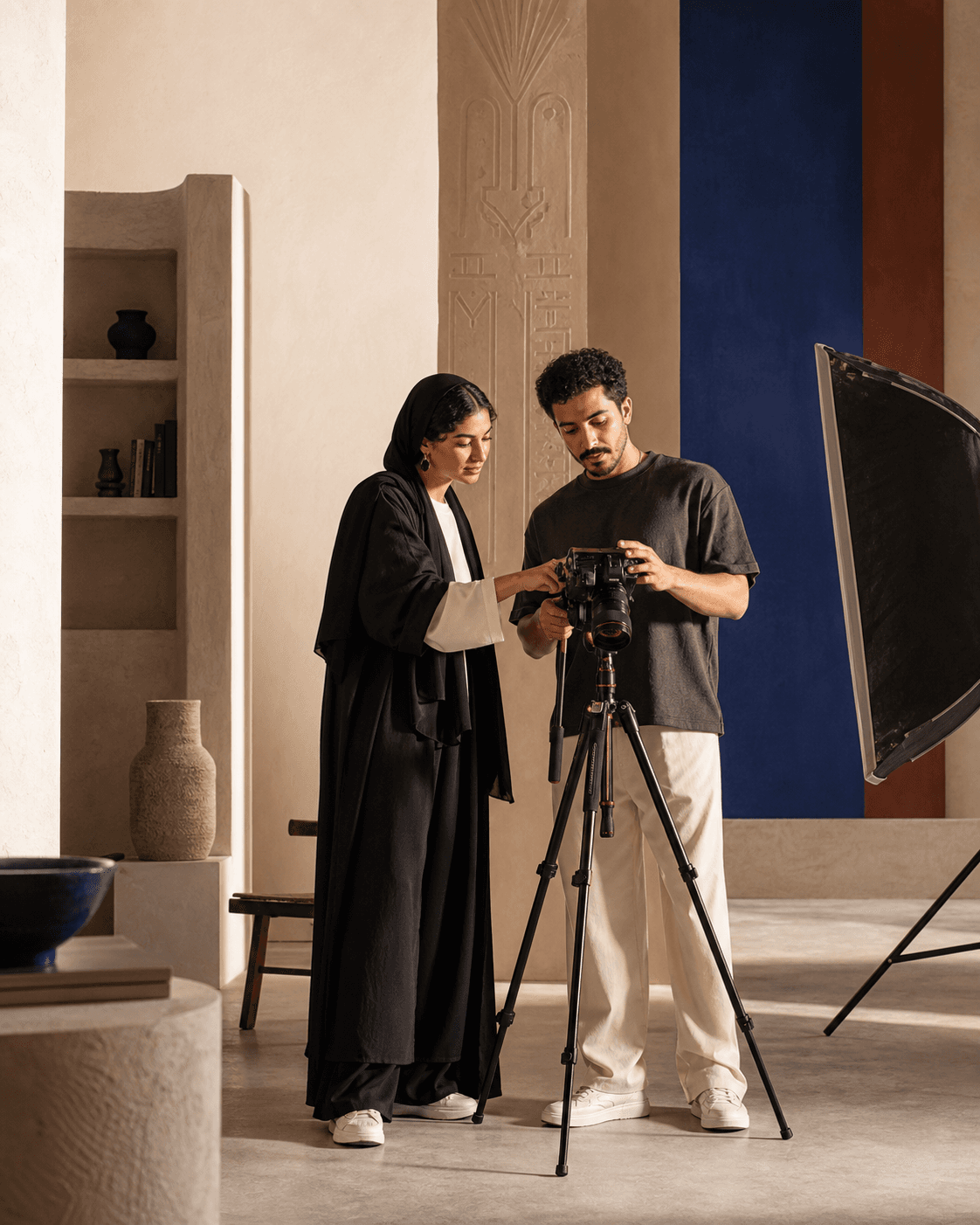 Two fictional MENA creators reviewing a camera in a warm contemporary studio